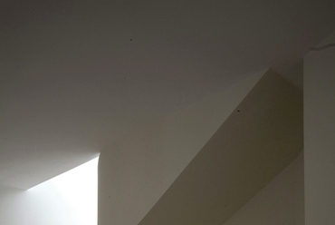A nappaliból a galériára vezető íves lépcső a kandalló blokkal együttszoborszerű központi elemet alkot, ami egyben biztosítja a mögötte lévő,olvasásra és tv-nézésre szolgáló térrész intimitását - tervező: Jankovics Gergő - fotó: Zsitva Tibor