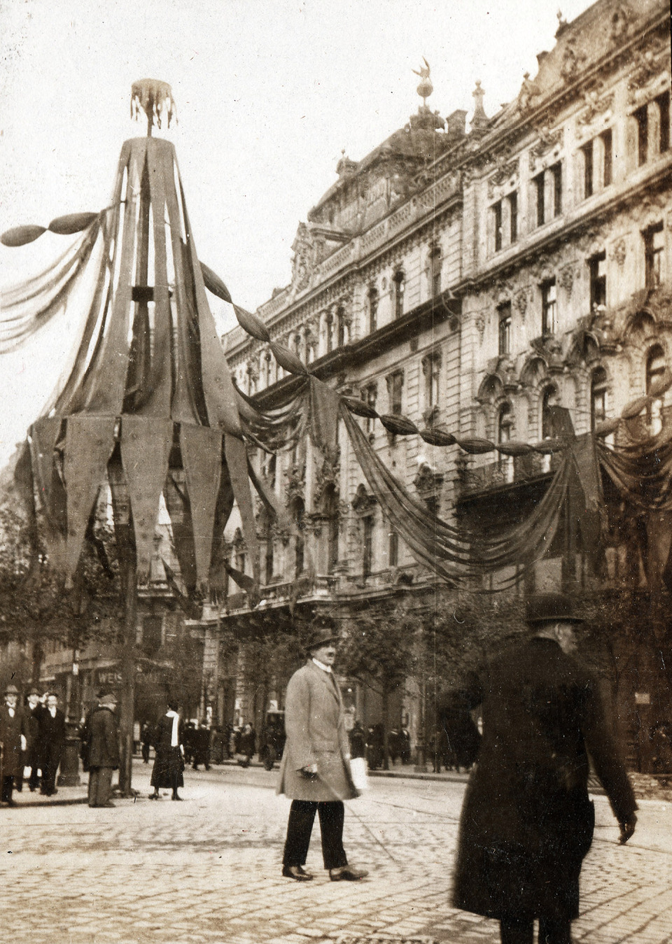 A Kossuth Lajos utca dekorációja 1919. május 1-én. A nagyszabású köztér-átalakítás bizonyos elemei a korábbi uralkodói ünnepségek örököseinek tekinthetőek. Fotó: Fortepan / Péchy László