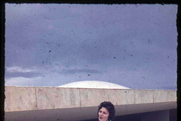 Jól öltözött hölgy a Brazil Nemzeti Kongresszus Oscar Niemeyer tervezte palotája előtt Brazíliavárosban