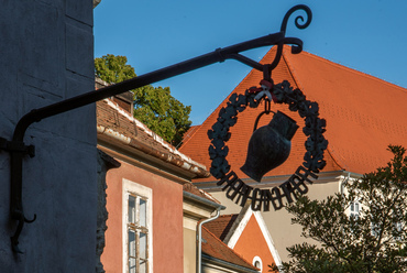 Az utca folytatásában álló, lépcsős homlokzatok, és a nagy múltú városi borozók egyike, a Kispanci, amelynek Kodolányi László ötvösművész által készített cégérét nehéz eltéveszteni.